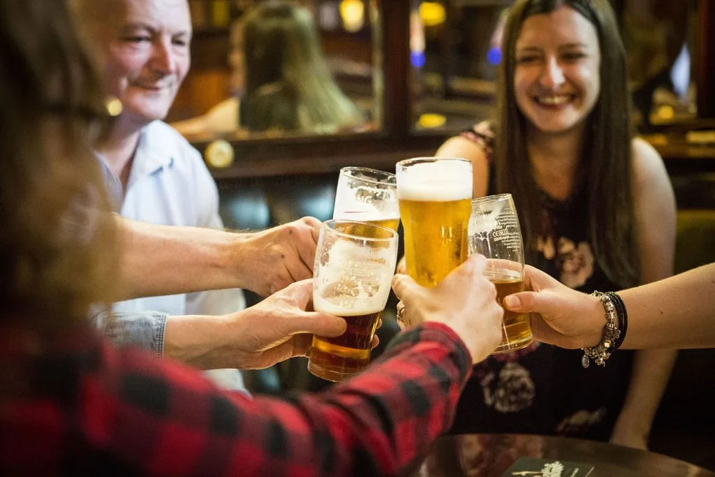 People toasting their drinks inside a pub